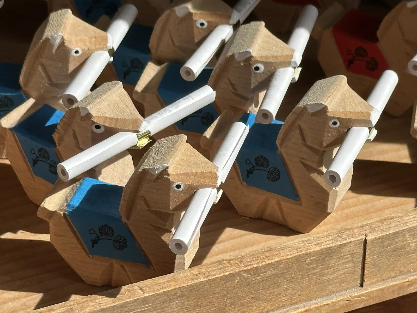 Wooden horse omikuji figurines holding rolled fortune slips